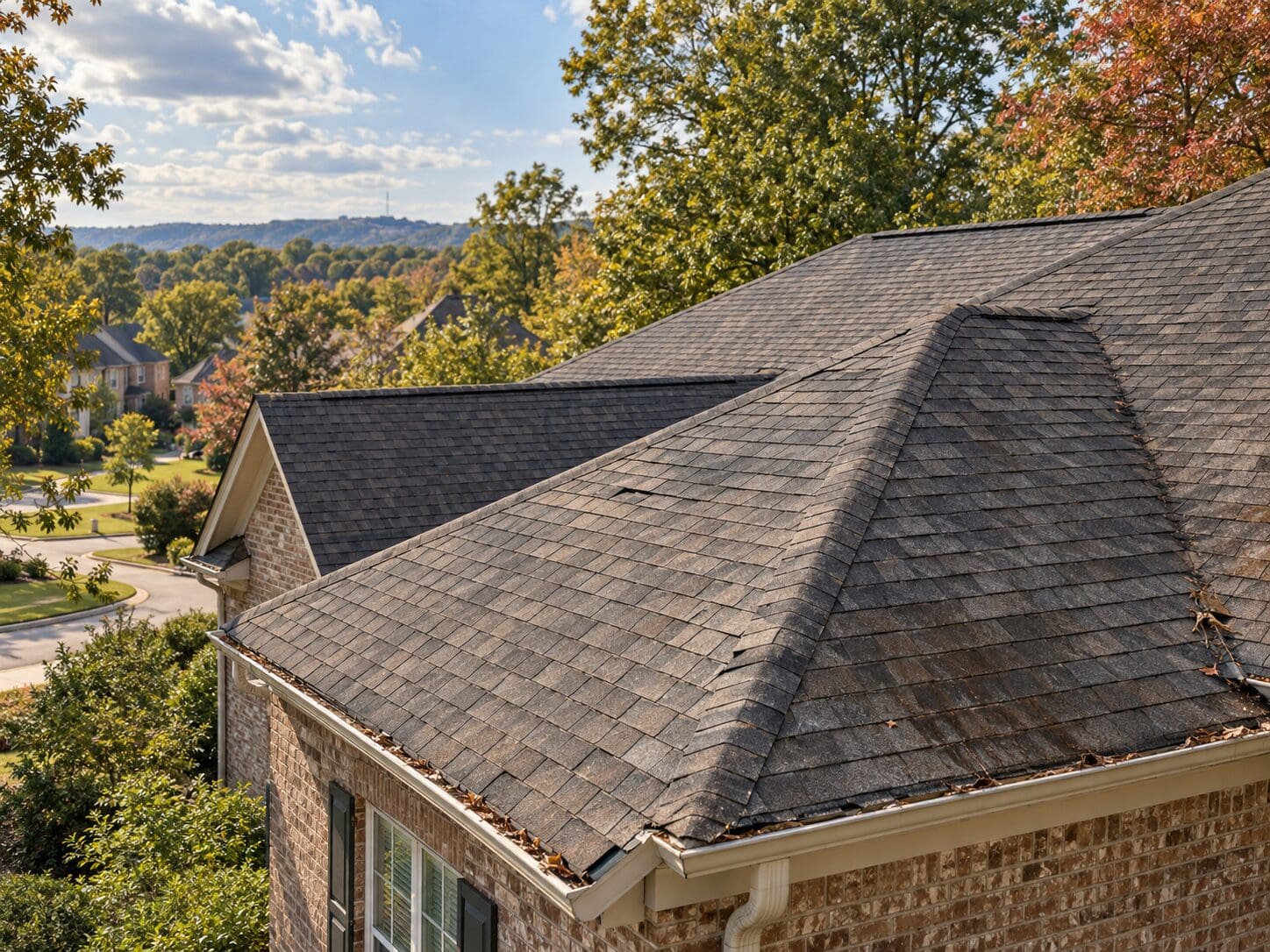 2943d63c-54d5-4555-bfa3-56b3092be94a Birmingham AL home with an asphalt shingle roof showing minor granule loss, light debris near gutters, and subtle roof wear before fall storm season.
