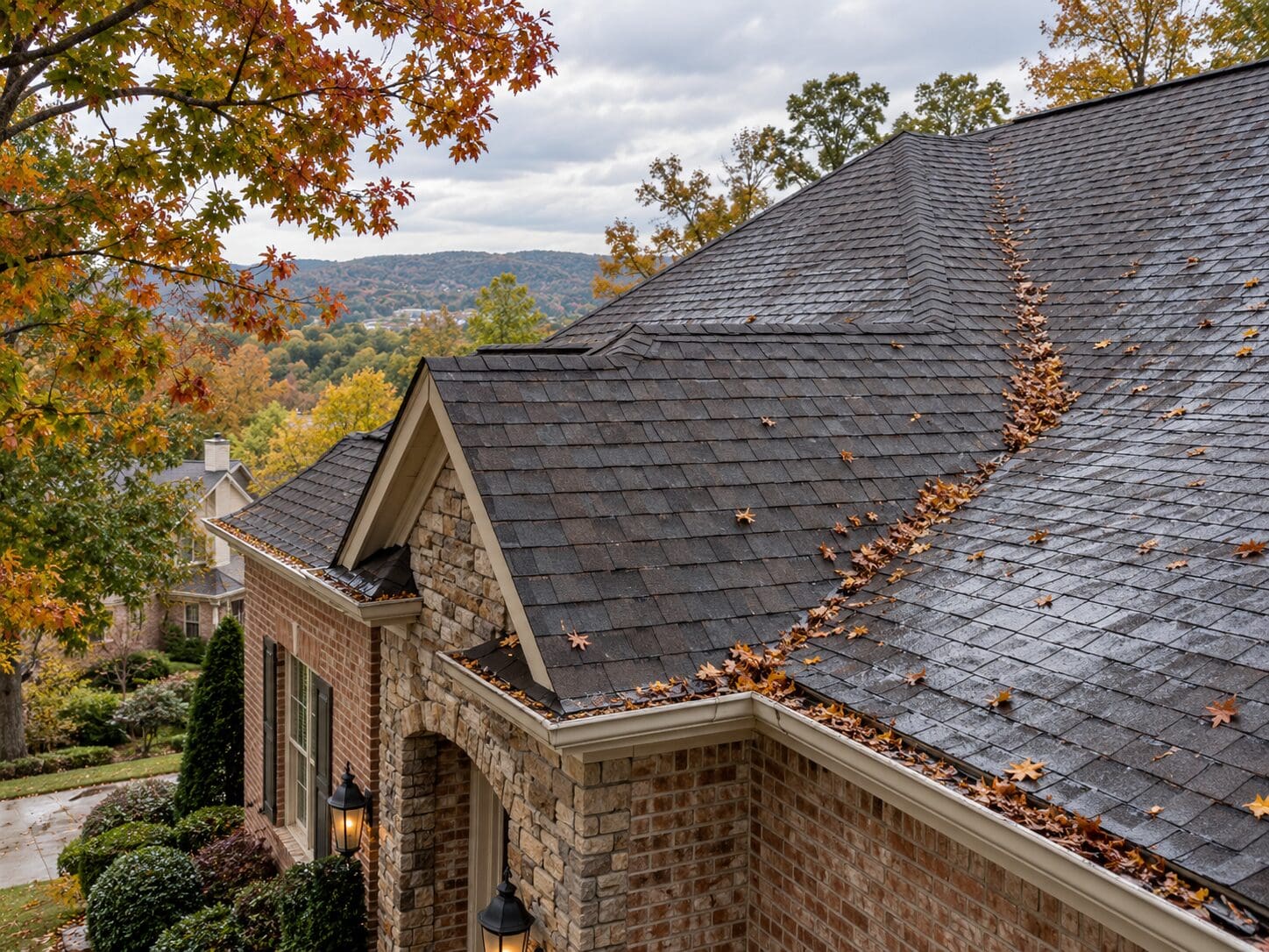 birmingham-al-fall-roof-maintenance-rooflab.png Birmingham AL asphalt shingle roof in early fall with wet shingles, light leaf buildup, roof valley debris, and minor roof-edge staining after rain.